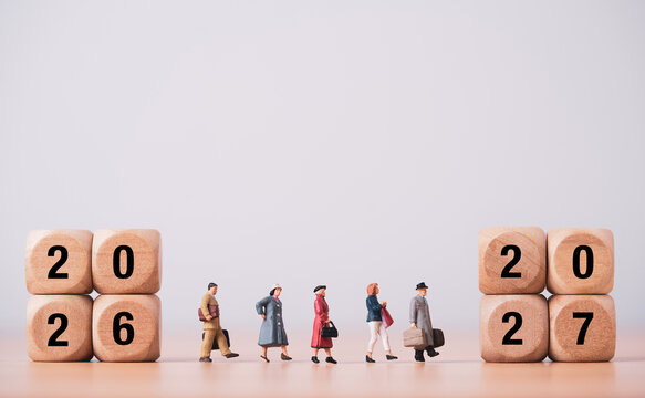 Miniature people walking from 2026 to 2027 blocks symbolizing for new business beginnings transformation, future planning and preparation new year transition concept.