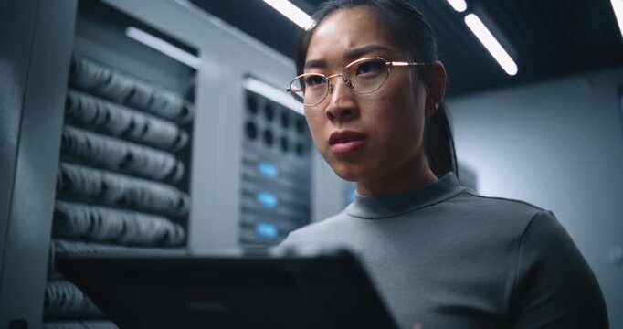 Young Woman in Data Center Examines Tablet With Worried Expression. Professional Scene Represents Network Diagnostics, Incident Assessment, Infrastructure Monitoring and Critical Technology Support.