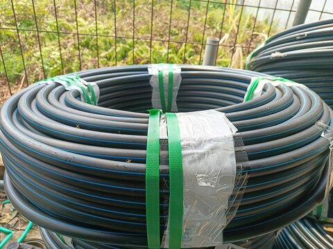 Pile of coiled black MDPE water pipe for plumbing systems
