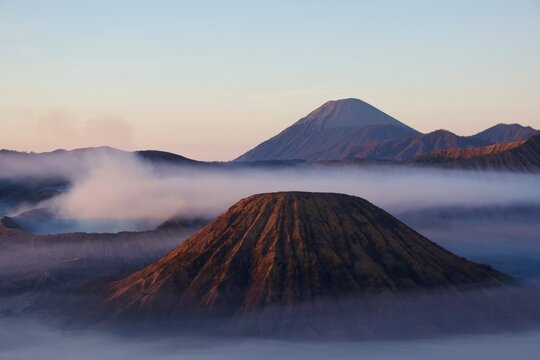 Sunrise over Mount Batok and Mount Bromo volcanoes with Semeru in the distance, fog in Tengger caldera, East Java, Indonesia