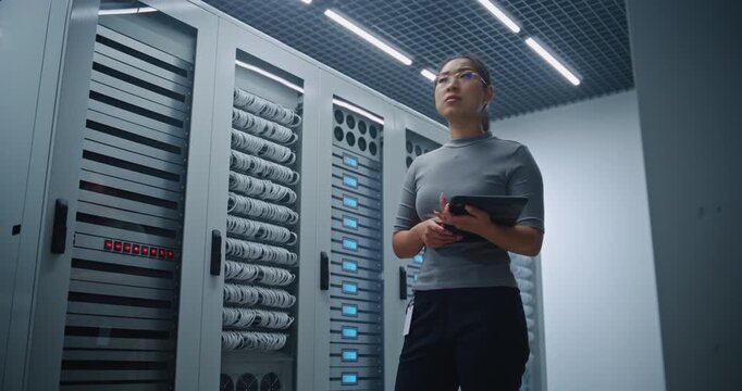 Female Technician Checks Dense Network Cabling While Using Tablet For Infrastructure Inspection in Modern Server Room. Connectivity Management, IT Maintenance and Reliable Digital Operations Onsite.