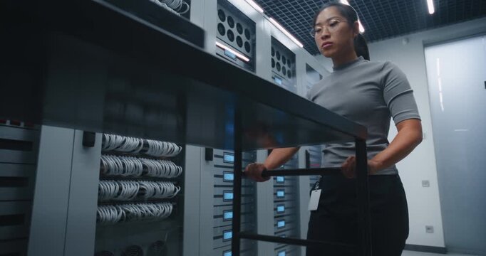IT Specialist Transports Network Switch on Metal Trolley, Opens Server Rack and Unplugs Network Cables. Workflow Shows Equipment Replacement, Connectivity Maintenance and Data Center Support.
