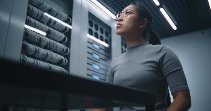 Female Network Engineer Brings Replacement Switch into Server Room, Accesses Rack and Disconnects Patch Cables. Service Demonstrates Hardware Upgrade, Cable Management and Preventive Maintenance.