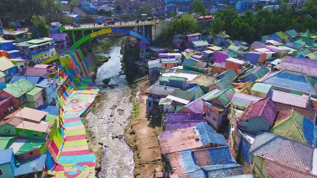 Aerial drone orbit shot revealing Jodipan Colorful Village, also known as Kampung Warna-Warni, a famous Malang tourism destination with colorful houses and urban art. East Java, Indonesia.
