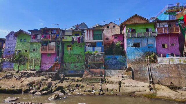 Riverside view of Jodipan Colorful Village, also known as Kampung Warna-Warni, featuring colorful houses, balconies along the river. East Java, Indonesia.