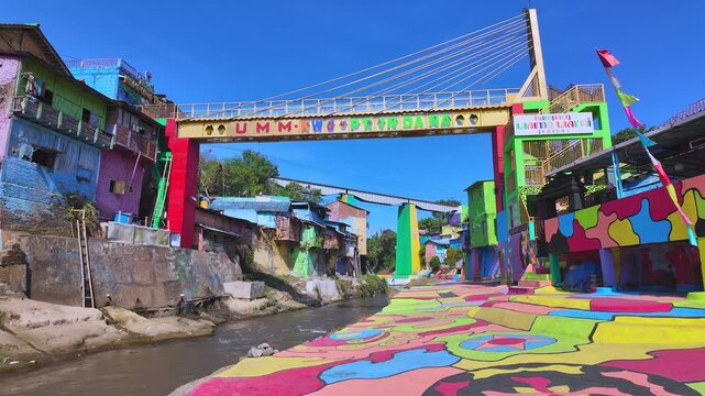 Riverside view of Jodipan Colorful Village, also known as Kampung Warna-Warni, a famous Malang tourism destination featuring colorful houses and a brightly painted bridge. East Java, Indonesia.
