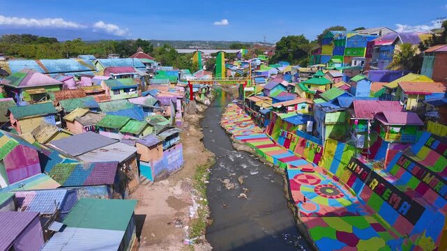 Elevated landscape view of Jodipan Colorful Village, also known as Kampung Warna-Warni, a tourism destination with colorful houses, urban art, and the riverside neighborhood. East Java, Indonesia.