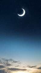 A glowing crescent moon shines brightly in a starry twilight night sky with soft clouds and a warm sunrise glow on the horizon. Nature, travel, or quotes background © Leo Lintang