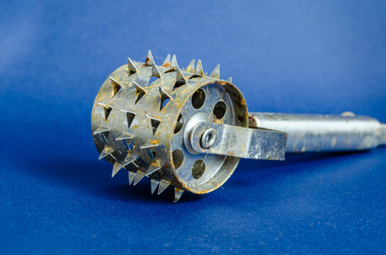 Metal pastry docker roller with spiked wheel on a blue surface