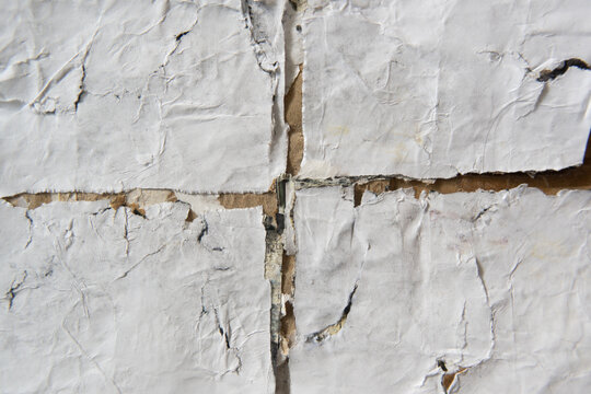 Decayed White Paper Glued on Wall Surface with Cross Shaped Gap in Center