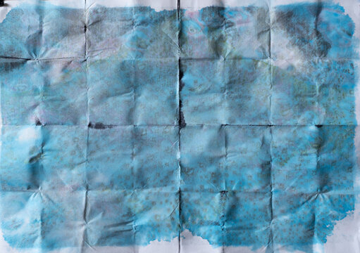 Paper with Fold Creases Divided into Thirty Two Little Blocks Stained with Blue Ink All Over