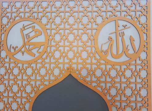 Close up view of wooden laser cut Arabic calligraphy of Allah and Muhammad with Islamic geometric pattern wall decoration.