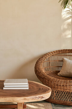 Worn hardback books on live edge table beside curved rattan armchair in warm interior