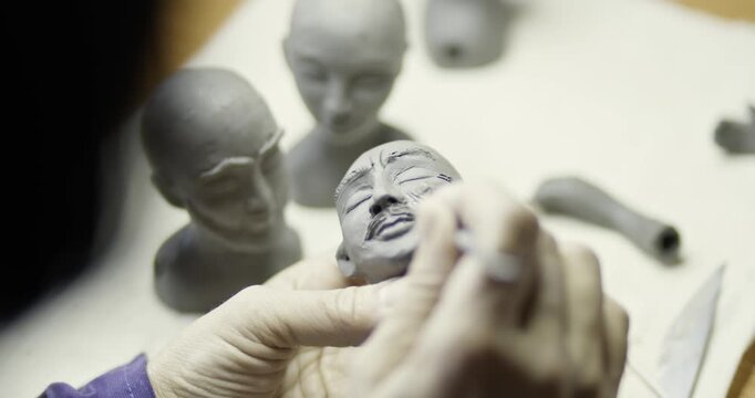 Artist painting facial details on handmade doll head close up
