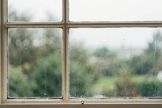 Rain beaded on the glass of a painted sash window
