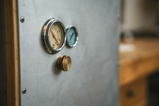 Two analogue gauges and a brass knob on a steel panel