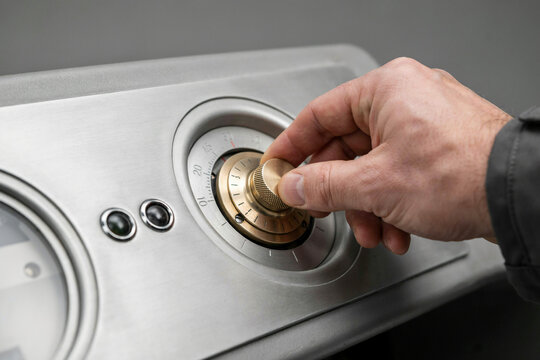 A hand turning a knurled brass dial on a steel panel