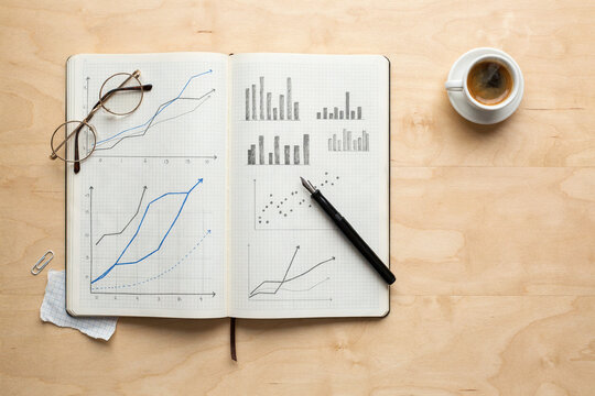 An open notebook of hand-drawn line and bar charts
