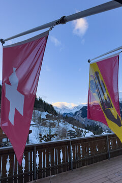 Scenic view Lauterbrunnen Valley with flags of Switzerland and Canton Bern seen from Wengen against snowcovered mountains in winter and blue sky with clouds in the morning