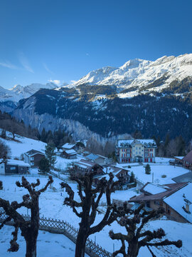 Scenic view of Wengen and Lauterbrunnen Valley, Switzerland with snowcovered mountains in winter against blue sky with clouds in the morning