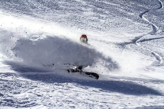 Snowboarder carves hard kicking up deep powder snow