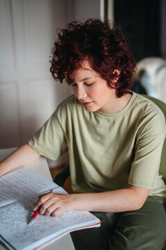 Teenager girl studying with a notebook beside a desktop