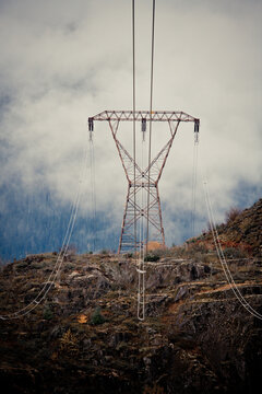 High voltage power lines and tower on a moody mountain landscape