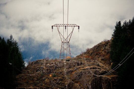 Electricity pylon and power lines on a foggy mountain hillside