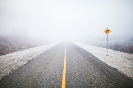 Empty country road disappearing into thick fog