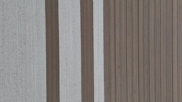 Alternating pale seedbed and dark brown soil strips with drill lines beside furrowed earth seen straight down in flat light, Po Valley, Italy, slow motion static top down drone hover