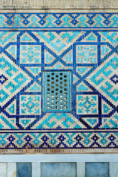 Geometric tilework and lattice window on Sher Dor Madrasah at Registan Square in Samarkand. Intricate blue and turquoise glazed brick mosaic showcasing Islamic architectural detail, ideal for travel.