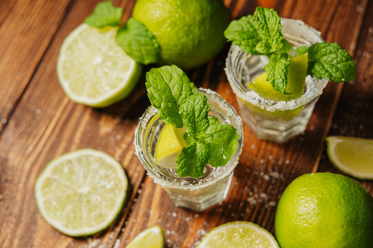 Two shots with lime and mint on a wooden table