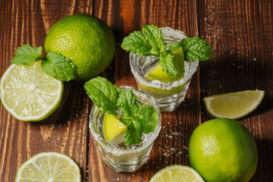 Cocktails with mint and lime garnished on wooden background