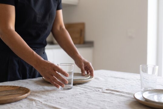 Hands arranging drinking glasses for a shared meal
