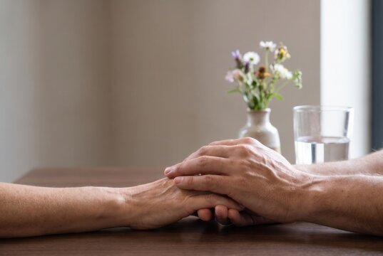 Close up of a couple holding hands at a restaurant table