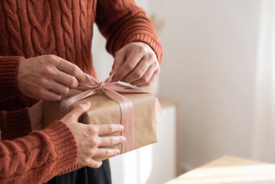 Hands tying a ribbon around a romantic gift box