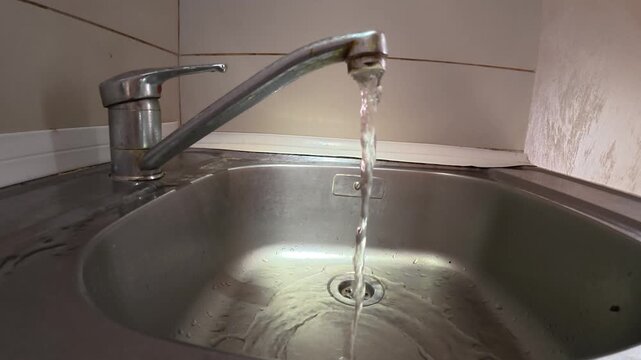 Tap Water Flowing into Stainless Steel Kitchen Sink