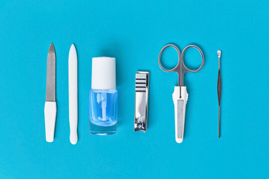 Manicure set and nail polish arranged in a row on blue background