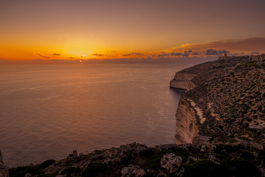 Wide Panoramic Sunset Landscape of Dingli Cliffs Coastline and Open Ocean with Golden Glowing Sky, Southwest Malta