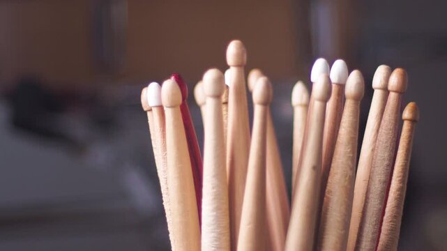 Wooden matches stand upright in a bundle beside a red-tipped match in a room