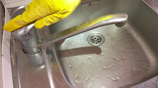 Top View of Hand Turning on Faucet Water in Kitchen Sink
