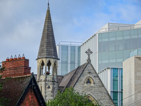 Historic Gothic church tower beside modern glass office building in Dublin Ireland