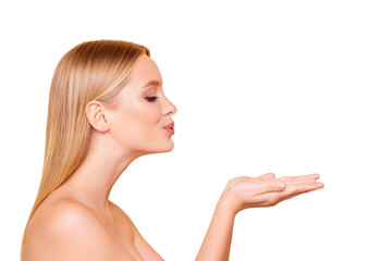 Profile portrait of cute, lovely, charming model blowing kiss with pout lips holding copyspace empty place on two palms looking at product isolated on beige background, advertisement concept © deagreez