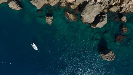 Aerial view of a yacht or boat in green sea by the coast with rocks   © raeva