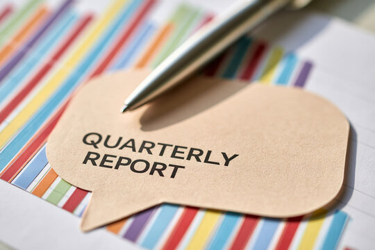 Quarterly report text on speech bubble with pen and colorful financial chart background. Financial analysis concept for corporate business presentation.