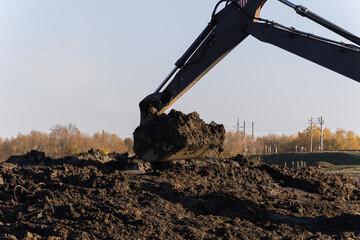 Excavator bucket digging dark soil at construction site industrial earthworks copy space © Sveta