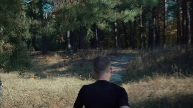 Athlete Running From On Dirt Path Through Forest Trees During Endurance Training