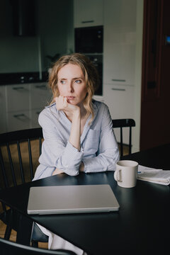 Woman experiencing a bad mood and irritability associated with premenstrual syndrome while sitting at home with a closed laptop, feeling unmotivated and emotionally drained during PMS