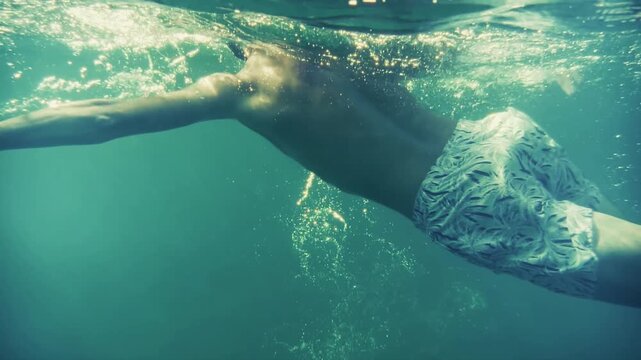 Swimmer Gliding Underwater Through Clear Sea Water While Creating Bubbles 