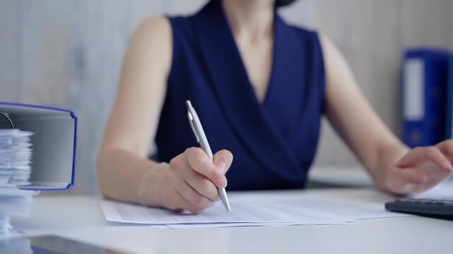 Unknown accountant businesswoman is using calculator and taking notes. Taxes, audit in business